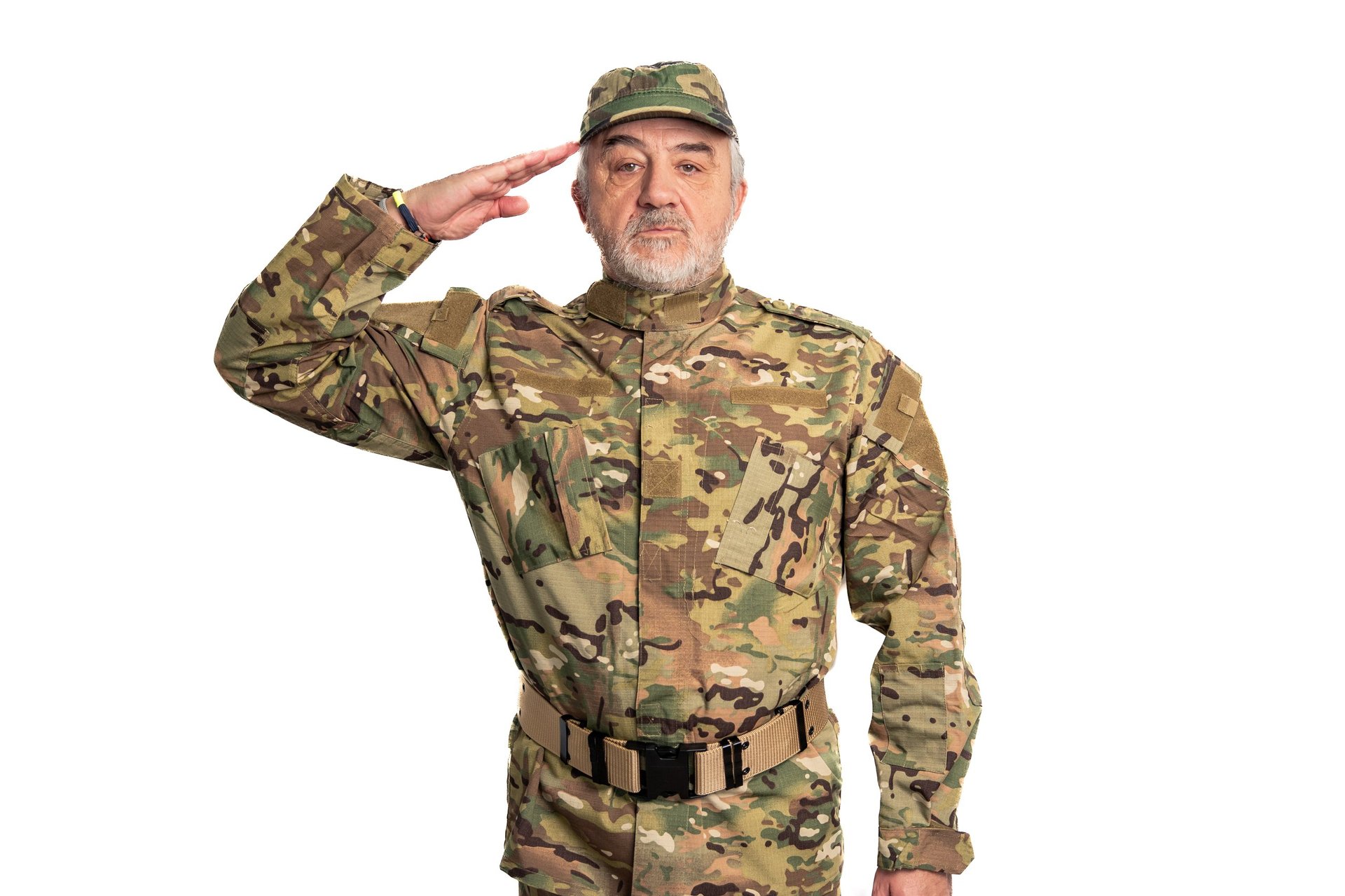 Senior adult military man proudly saluting while wearing a camouflage uniform and cap, showing patriotism, dedication, and respect on a clean white background